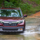 A photo of a Honda Ridgeline pickup truck driving through a stream.